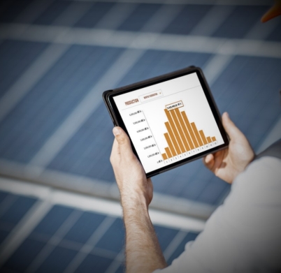 Man examining genaration of solar power plant, holding digital tablet with a chart of electricity production. Concept of online monitoring of the electric station